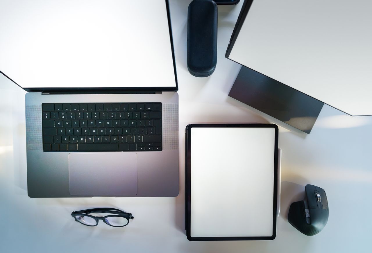 Vue plongeante d’un bureau moderne et élégant avec un ordinateur portable, une tablette et des accessoires.